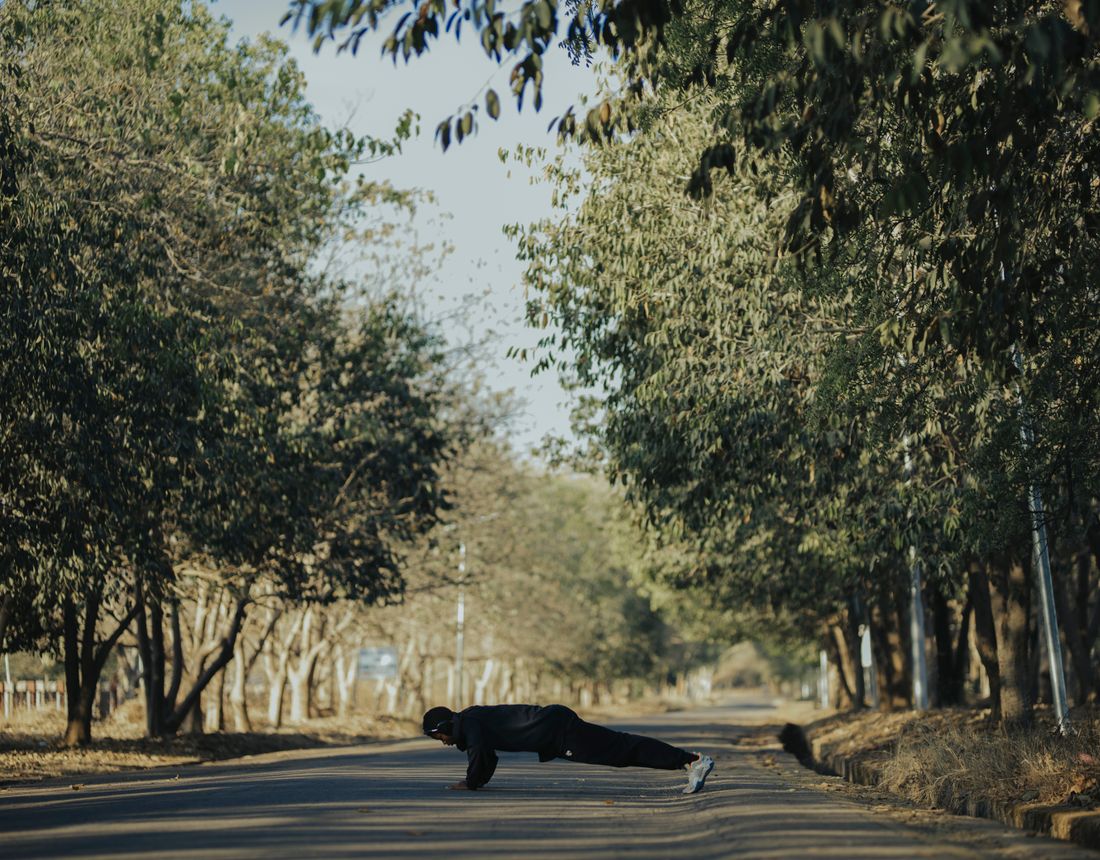 Person training outdoors on a tree-lined road
