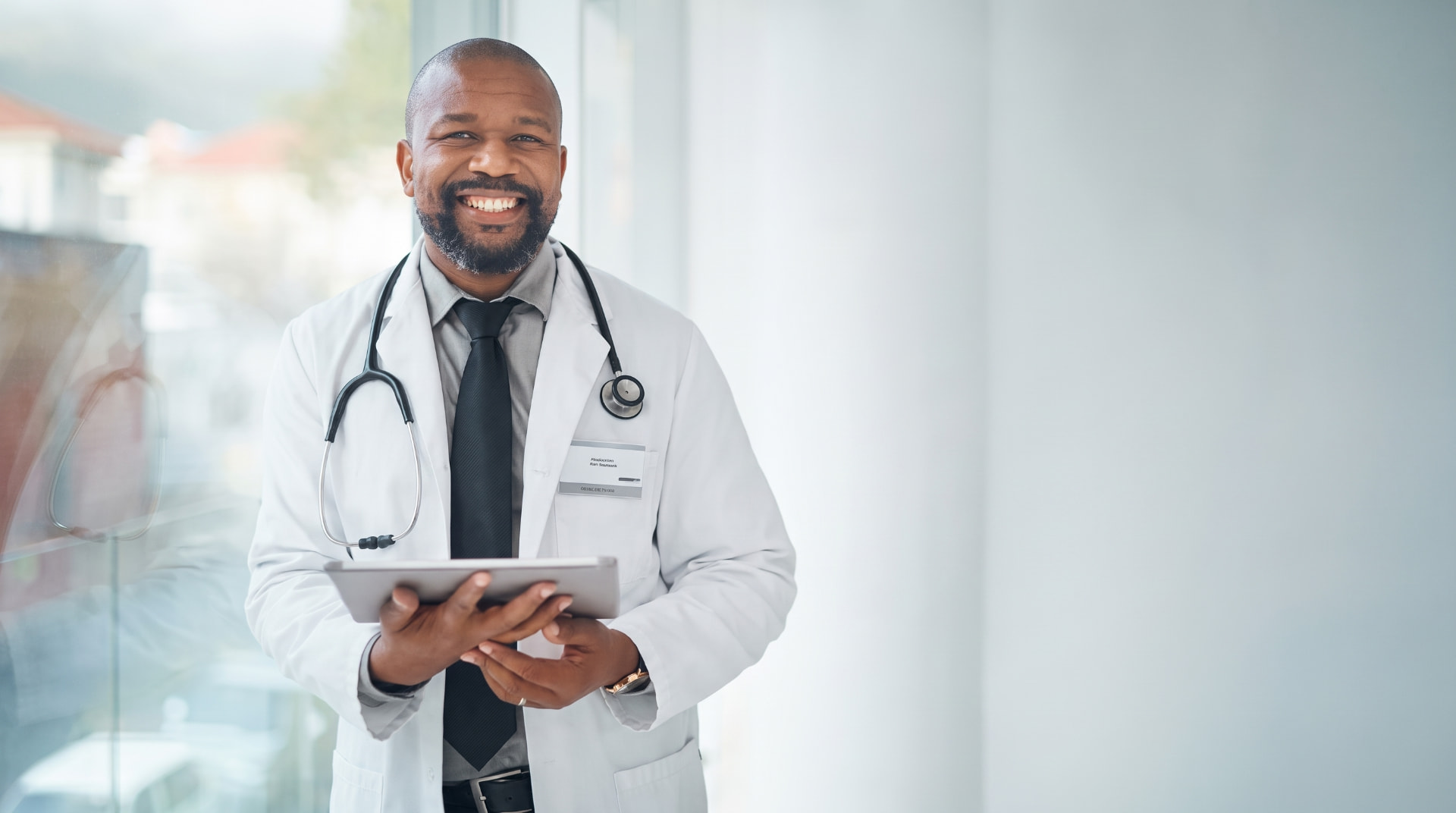 Smiling physician holding a tablet in a bright clinic