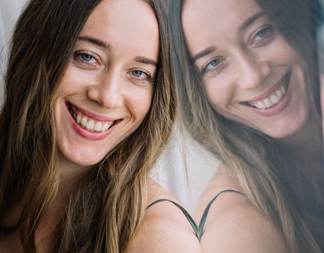 Two women smiling outdoors with healthy, glowing skin